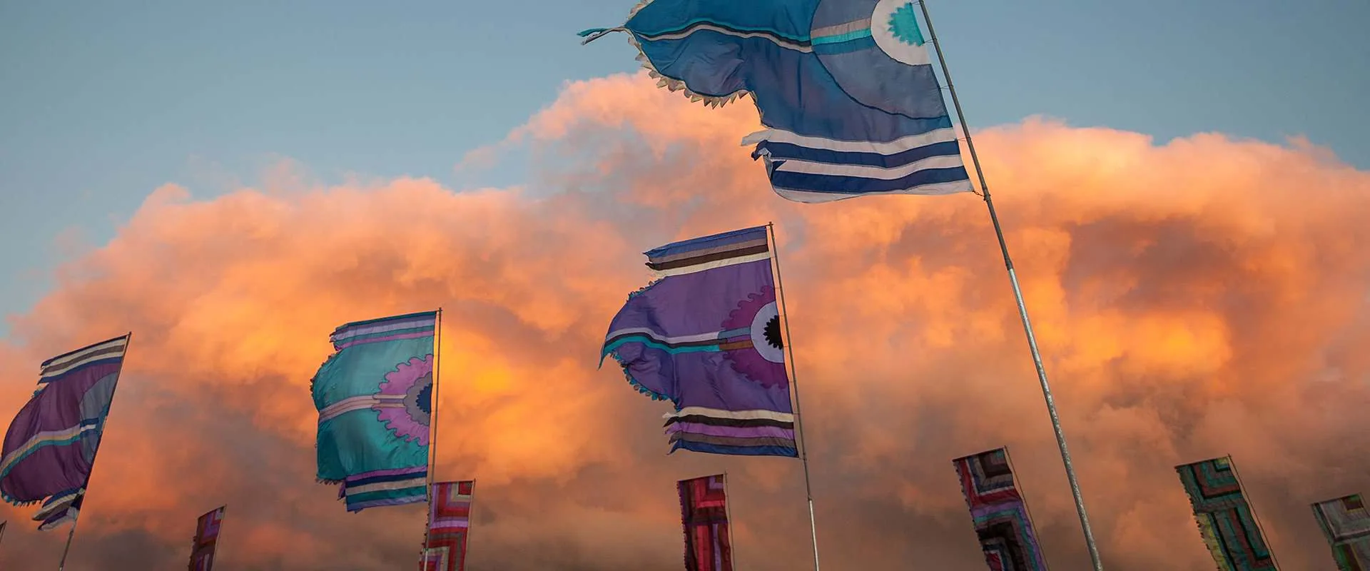 colourful torn flags flying at sunset at WOMAD festival